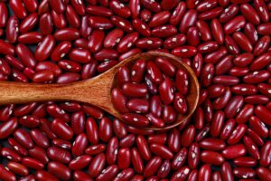 Close-up of red kidney beans and a wooden spoon, showcasing vibrant color and texture.