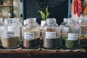 Glass jars in a store containing organic seeds like quinoa and flax, promoting sustainable living.